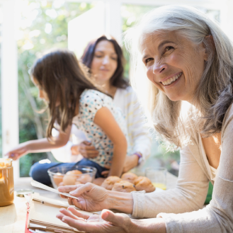 Grandmother, who represents a potential Protective Secure Saver fixed annuity customer, reviews recipe while cooking with daughter and granddaughter.