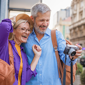 Retired man and woman smiling while looking at a photo on their camera.