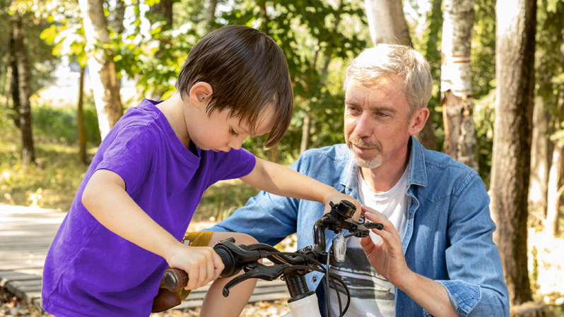 A father teaching his son how to ride a bike.