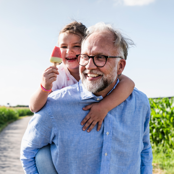 A man carrying his granddaughter on his back.